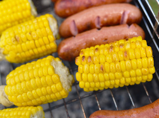 corn on the cob and sausages roasted on the coals
