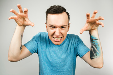 Young frightening guy dressed in a blue t-shirt, isolated on a light background.