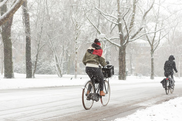 Woman biking in a snowy Amsterdam Vondelpark.