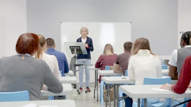 Female speaker giving presentation for adult students in lecture hall 