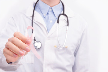 Oncological disease concept. Doctor wearing white coat and stethoscope holding pink ribbon as a symbol of breast cancer.