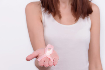 Oncological disease concept. Girl wearing white top holding pink ribbon as a symbol of breast cancer in her hand.