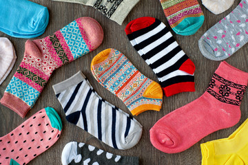 Multicolored knitted socks. Many socks with a different pattern on a wooden background. Warm...