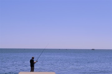 рыбак с удочкой на море