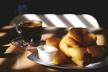 Deep-fried dough stick place in front of black coffee in clear glass.For a simple breakfast.