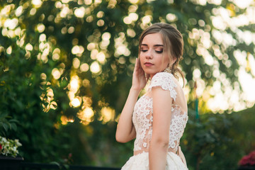 Young girl in wedding dress in park posing for photographer