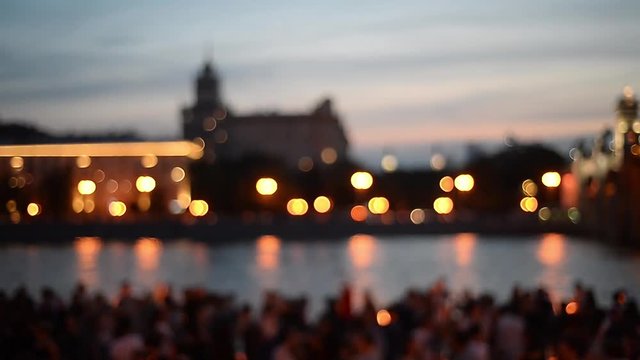 Dancing on a hot summer night on the waterfront. Defocused image. Night lights and silhouettes