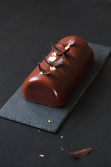 Ptichye Moloko (Bird's Milk) - traditional Russian Vanilla Souffle Cake, covered with chocolate glaze and decorated with chocolate feathers, on black background.