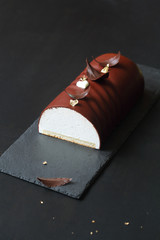 Ptichye Moloko (Bird's Milk) - traditional Russian Vanilla Souffle Cake, covered with chocolate glaze and decorated with chocolate feathers, on black background.