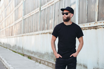 Hipster handsome male model with beard wearing black blank t-shirt with space for your logo or...