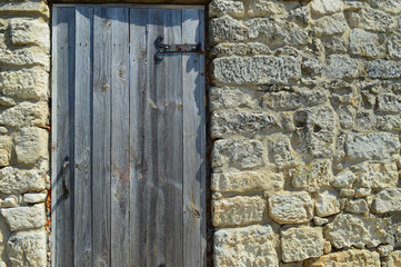 A wooden door with metal hinges is installed in the wall