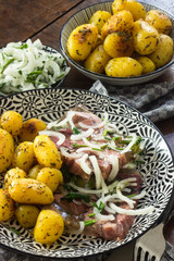 Fleischsülze mit Bratkartoffeln und Zwiebelringen auf einem Teller angerichtet