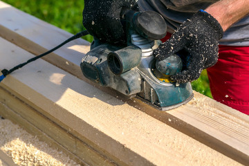 man planing boards with electric tools, chips flying in all directions. Construction, wood processing