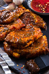 Steakfleisch für den Grill würzen mit Chillsauce auf dunklem Untergrund