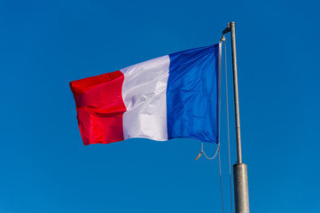 French flag waving against blue sky in Boulogne sur Mer, France.