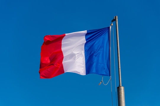 French flag waving against blue sky in Boulogne sur Mer, France.