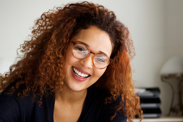Obraz premium Close up happy young woman with curly hair and glasses