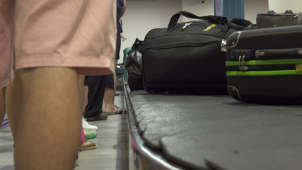 CLOSE UP: Unknown passengers wait to collect their baggage after a long flight.