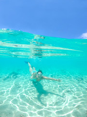 HALF UNDERWATER: Active woman on holiday snorkels in ocean and gives the ok sign