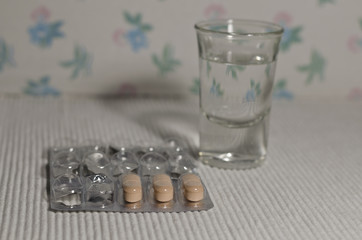 Some prescribed pills with a glass of water