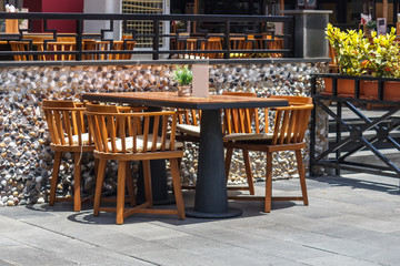 Sunny summer day, near the cafe on the street is a table with chairs.Sunny summer day, near the cafe on the street is a table with chairs.