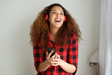 young woman with curly hair listening to music with headphones and mobile phone