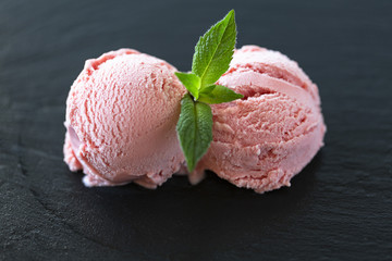 Strawberry Ice Cream balls  In Bowl with mint over black background.