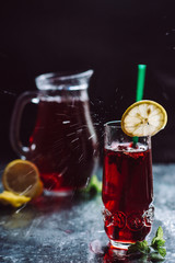 Cold refreshing berry drink with ice, mint and lemon close up