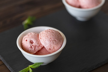 Strawberry Ice Cream balls  In Bowl with mint over black background.
