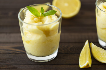 Fresh lemon citrus sorbet garnished with mint alongside.  Lemon Frozen Granita Slush Drink. 