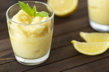 Fresh lemon citrus sorbet garnished with mint alongside.  Lemon Frozen Granita Slush Drink.  - obrazy, fototapety, plakaty