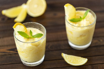 Fresh lemon citrus sorbet garnished with mint alongside.  Lemon Frozen Granita Slush Drink. 
