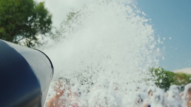 The cannon throws out the streams of foam on the people who are having fun on the beach. Foam beach party. No recognizable people in the frame