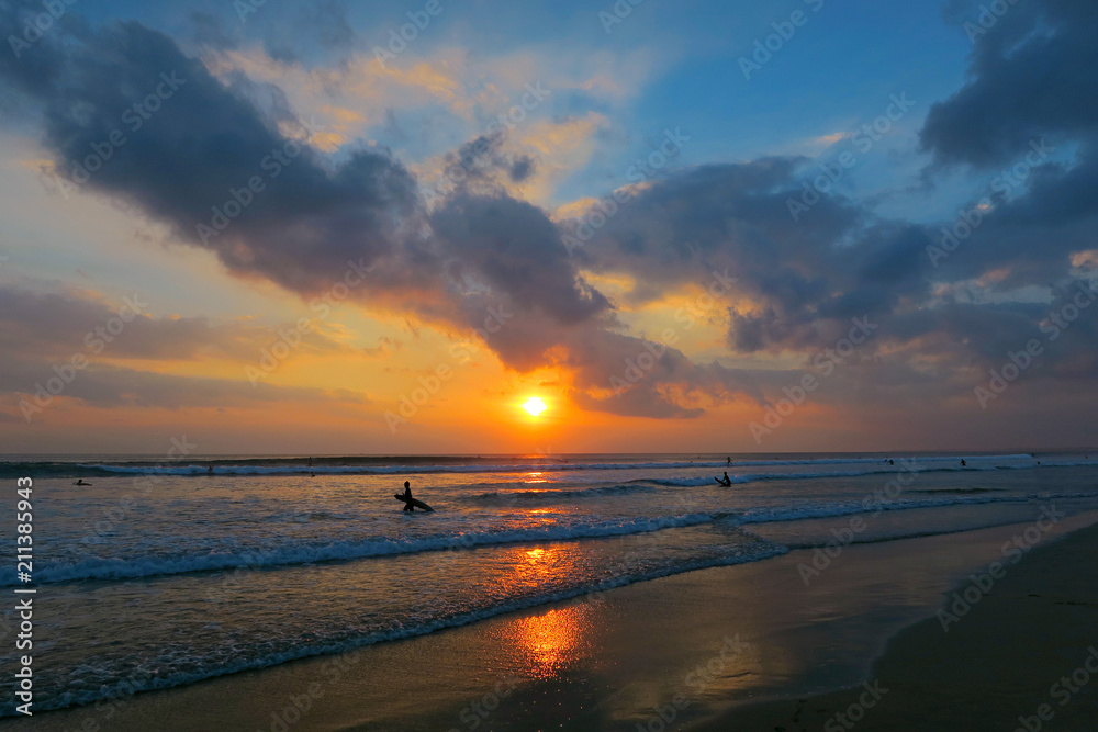 Wall mural Amazing Kuta beach sunset with ocean waves, surfers and reflection in wet sand, Bali, Indonesia