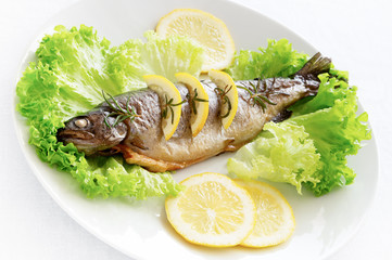 roasted trout decorated with rosemary and lemon served on lettuce leafs