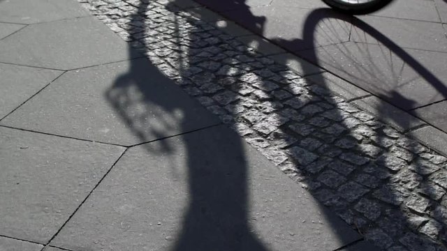 Slow Motion Shot Of Multiple Bicycle Riders In Shadow Cycling By On A Bicycle Lane In Berlin.