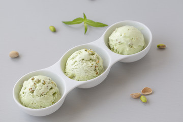 Pistachio ice cream in white bowl. Fresh pistachio ice cream, nuts and mint.