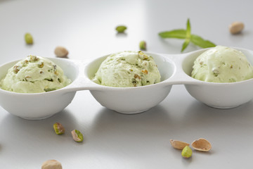 Pistachio ice cream in white bowl. Fresh pistachio ice cream, nuts and mint.