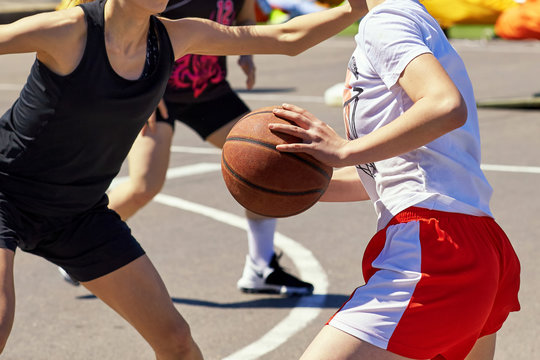 Girls teenagers play basketball.