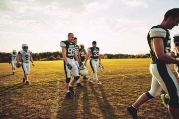 Smiling young American football players walking off a field toge © Flamingo Images