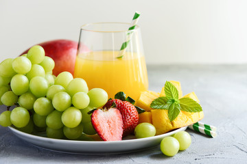 Mango juice, refreshing cocktail and fruits. Strawberries and grapes, healthy summer drink. Selective focus