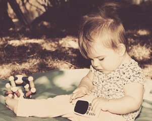Baby Girl Playing With Mobile Phone. Sephia Effect