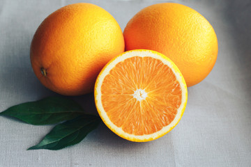 Half and whole oranges close up on a gray background.