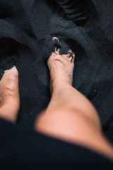 Obraz premium Woman's feet on black sand from above.