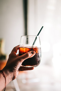 Woman's Hand Holding Glass Of Black Cold Brew Coffee With Ice. Hipster Coffee Shop. Minimalism Drink Photography