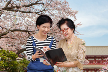 Senior woman reading a travel guidebook with her daughter