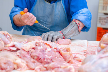 Chicken. Cutting shop of a poultry farm. Butcher is chopping a chicken