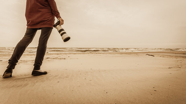 Woman walking on beach with camera