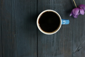 A cup of black coffee and an anemone flower