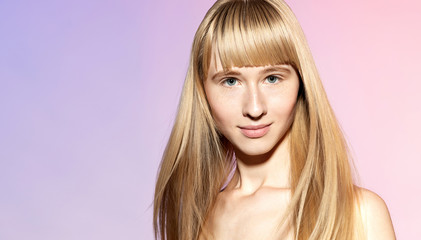 Naklejka premium Waist up portrait of gorgeous smiling blonde with nice long straight hair and perfect clean skin. Beauteous young woman posing at studio and looking at camera with tenderness